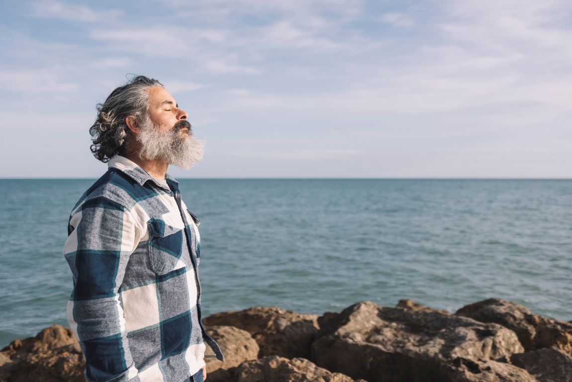 Nasal Obstruction Patient Needs Latera man breathing through nose on rocks near the ocean